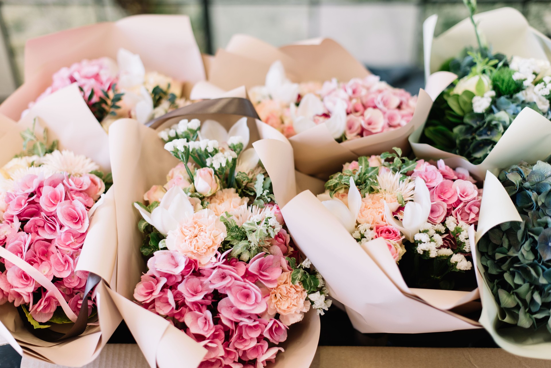 Viele Blumensträuße im Blumenladen auf dem Tisch aus Hortensie, Rosen, Pfingstrosen, Eustoma in rosa und meergrünen Farben